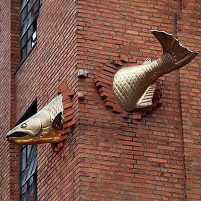 不锈钢穿墙的鱼雕塑